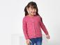 Une fille porte un pull rose à motif papillon et un jean.