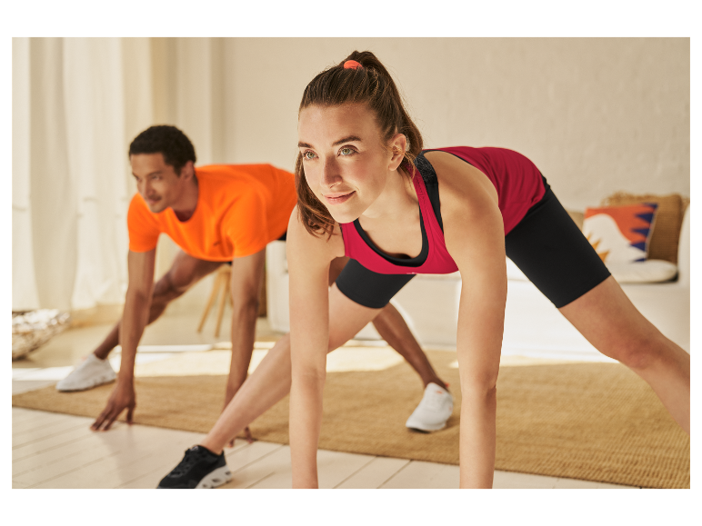 Deux personnes font des étirements dans leurs vêtements de sport à la maison.