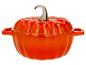 Cocotte en fonte orange en forme de citrouille avec poignée métallique.