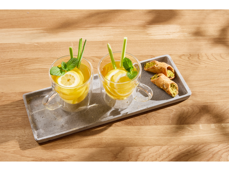 Deux verres de thé citron-menthe avec citronnelle, et deux cannoli sur un plateau.