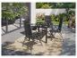 Ensemble de salle à manger d'extérieur avec table noire et quatre chaises pliantes grises sur un tapis de patio.
