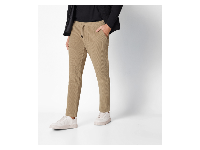 Pantalon beige en velours côtelé et baskets blanches.