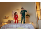 Enfants en pyjamas de Noël sautant sur un lit avec du linge de lit à carreaux.