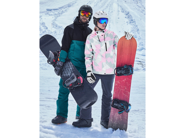 Deux snowboarders avec des casques et des lunettes tiennent leurs snowboards dans la neige.