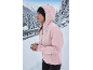 Femme en veste rose et bonnet noir dans un paysage hivernal enneigé.