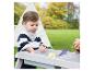 Enfant jouant avec une table de sable et d'eau en bois dans un jardin.