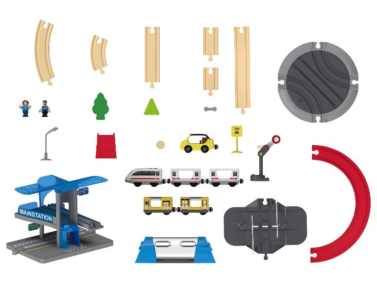 Une collection de pièces de jeu de train jouet comprenant des rails, des trains, une gare et des accessoires.