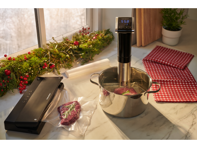 Machine sous vide et sous-vide avec de la viande cuisant dans une ambiance de Noël.