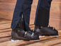 Des chaussures de ski avec un pantalon bleu sur un plancher en bois