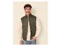 Homme souriant en gilet matelassé vert foncé, sweat-shirt clair et jean.