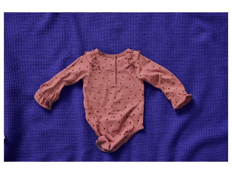 Body bébé rose à cœurs sur une couverture bleue