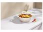 Poulet rôti avec légumes dans une cocotte crème sur un comptoir en marbre blanc.