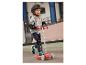 Un enfant roule sur une trottinette Playmobil rouge, équipé d'un casque et de protections.