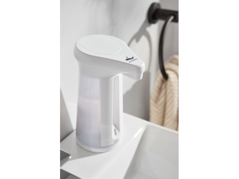 Distributeur de savon automatique blanc avec porte-serviettes noir et serviette beige.