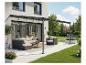 Patio moderne avec pergola, canapé d'extérieur, fauteuil et plantes en pot.