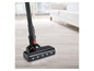 Un aspirateur noir avec éclairage LED sur un plancher en bois.
