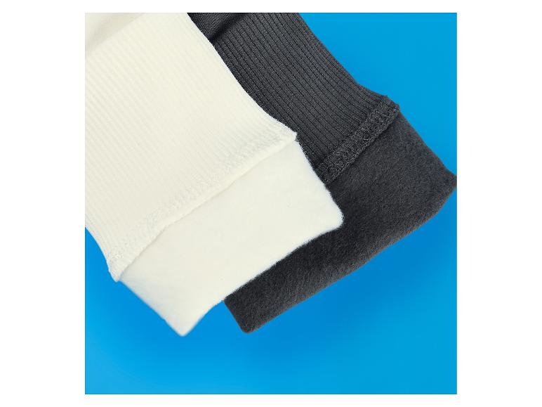 Poignets de pull côtelés crème et gris foncé sur fond bleu.