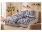 Lit avec parure de lit bleue et blanche à motifs, étagères en bois et plantes.