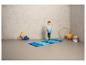 Un garçon debout sur un tapis de gymnastique bleu avec un ballon bleu.