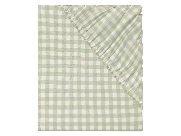 Un drap-housse à carreaux verts pour un lit simple.
