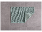 Un tapis de bain vert clair sur un sol carrelé gris.