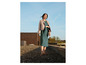 Une femme en robe verte et en veste en cuir rose sur un toit.