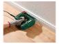 Main utilisant une agrafeuse électrique pour fixer une plinthe sur un plancher en bois.