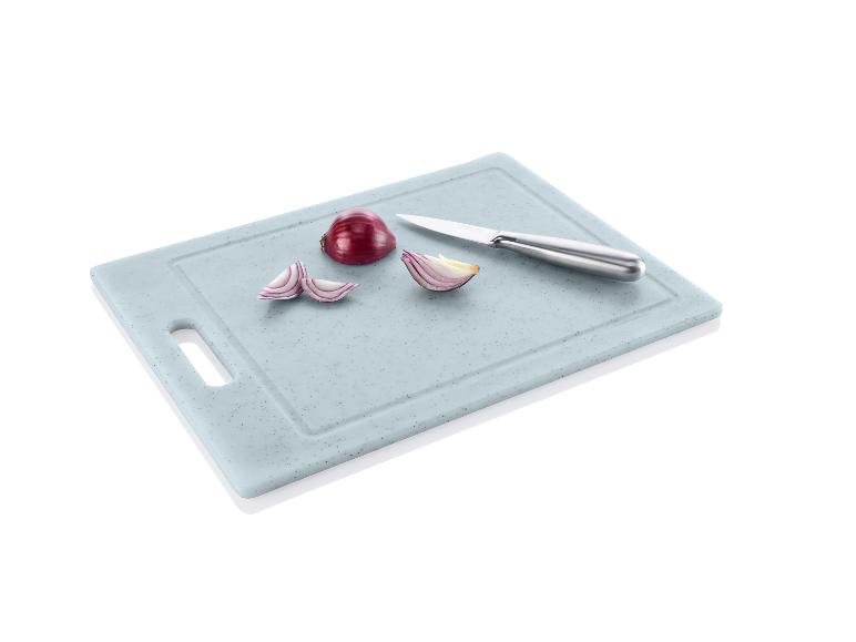 Une planche à découper avec des oignons rouges coupés et un couteau Ernsto.