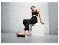 Une femme en tenue de sport utilise un rouleau en mousse pour ses pieds.