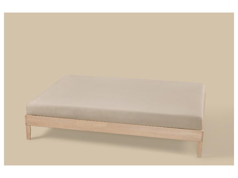 Drap-housse beige clair sur un cadre de lit en bois