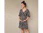 Une femme enceinte portant une robe noire à imprimé floral blanc.