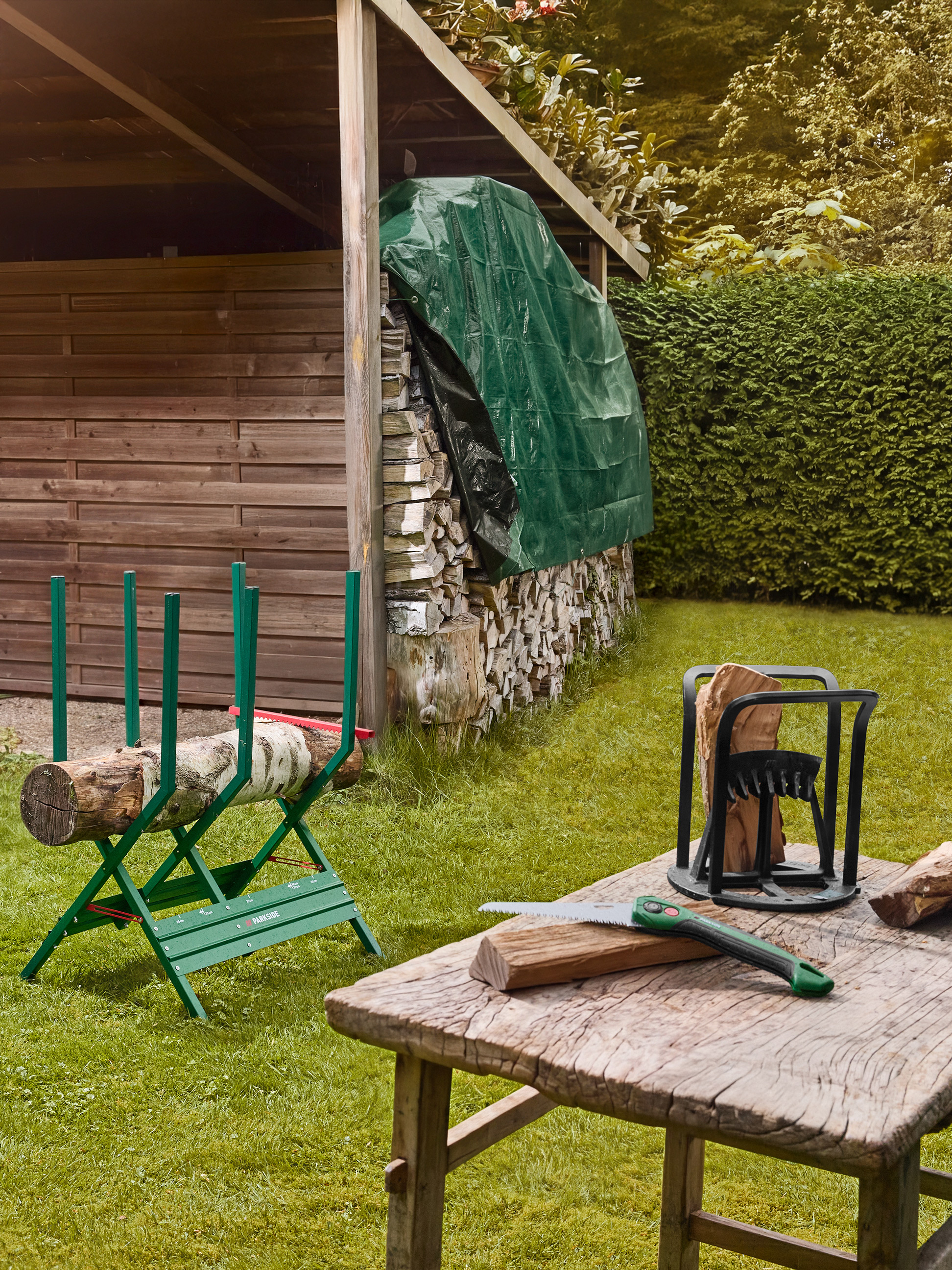 Chevalet de sciage et fendeur de bûches en extérieur, avec scie et bois sur une table.