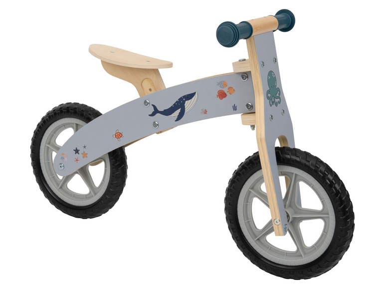 Un vélo d'apprentissage en bois avec un décor de baleine bleue et de pieuvre.