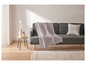 Un canapé gris avec une couverture rose et un coussin blanc.