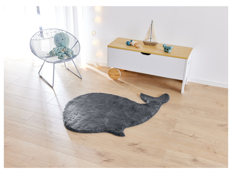 Un tapis gris en forme de baleine dans une chambre d'enfant avec une chaise et une armoire.