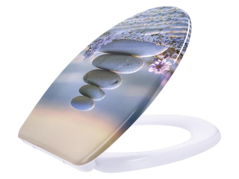 Abattant de toilettes avec un imprimé zen de pierres empilées et de fleurs.