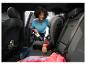 Femme aspirant l'intérieur de la voiture avec un aspirateur à main, avec siège enfant et bottes.