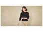 Une femme portant un pull noir et un pantalon beige.