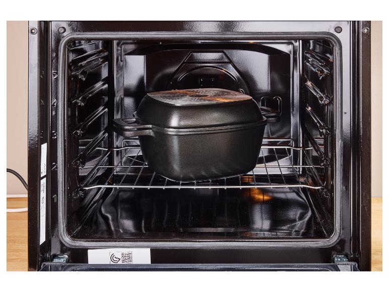 Four ouvert avec une cocotte noire sur la grille.