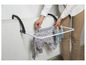Un séchoir à linge blanc avec un body de bébé et des chaussettes, fixé à un radiateur.