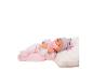 Poupée bébé en grenouillère rose avec bonnet et sucette, allongée sur un coussin blanc.