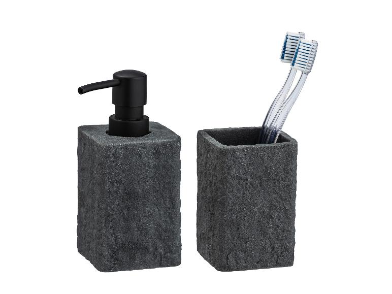 Distributeur de savon et porte-brosses à dents en pierre grise foncée.