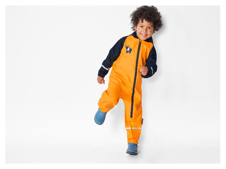 Un enfant porte une salopette de pluie orange avec un éléphant.