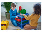 Deux enfants jouent avec des blocs Lego sur une table Lego bleue avec des tiroirs.