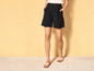 Une femme porte un short noir et des sandales blanches.