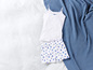 Un débardeur blanc et un pantalon de pyjama à fleurs bleues sur un lit blanc.
