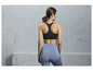 Femme en soutien-gorge de sport noir et leggings bleus.