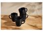 Ensemble de quatre mugs noirs mats sur une table en bois.