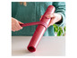 Une femme enroule un tapis de cuisson en silicone rouge de Coox.