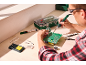Homme soudant une carte de circuit imprimé avec un fer à souder, de la soudure et des outils.